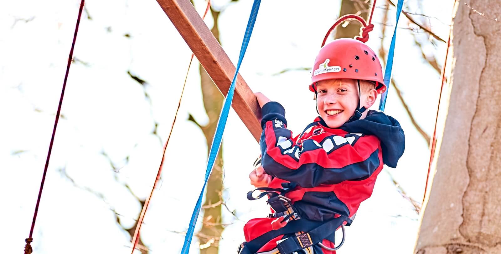 Junge im Halbportrt mit Kletterausrstung klettert in einem Gerst