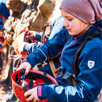 Mdchen in Kletterausrstung setzt sich einen Helm auf