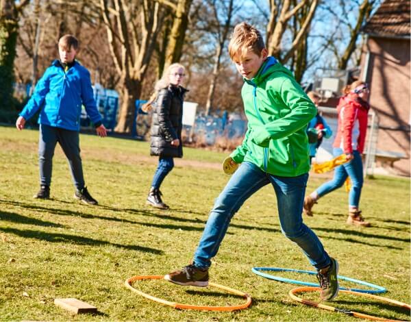 TeamTage Kinder spielen auf der Wiese ein Spiel mit Ringen